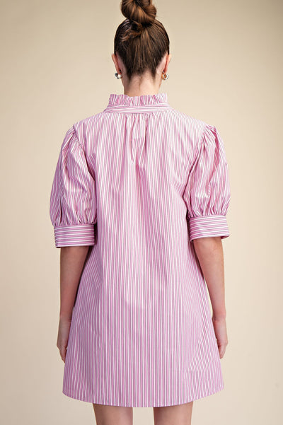 Person wearing a pink and white striped dress against a beige background