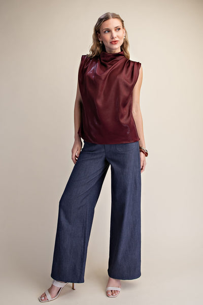 model wearing sleeveless shimmer burgundy top with jeans