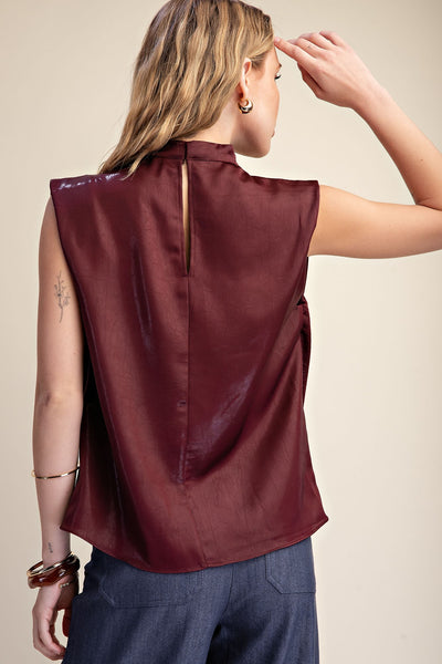 back of model wearing sleeveless burgundy top & jeans