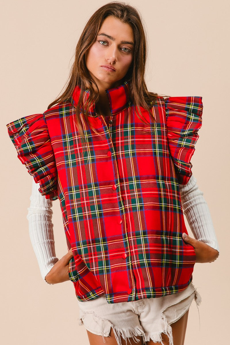 Woman wearing a red plaid vest with ruffled sleeves on a beige background