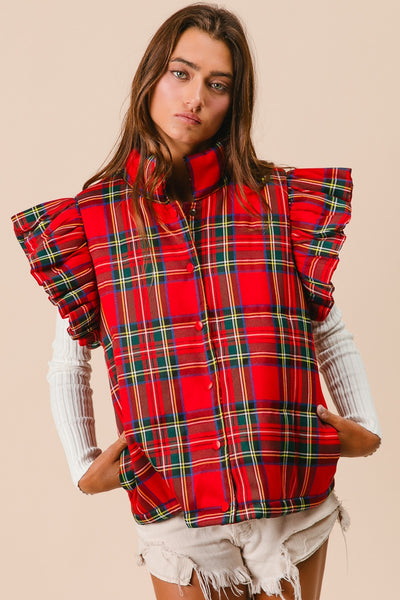 Woman wearing a red plaid vest with ruffled sleeves on a beige background