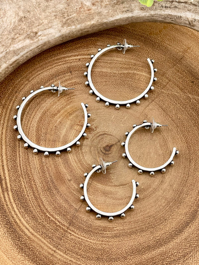 Set of silver hoop earrings with bead detailing on a wooden surface