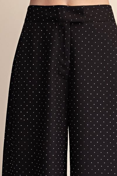Black wide-leg trousers with rhinestones, shown on a model against a neutral beige background.