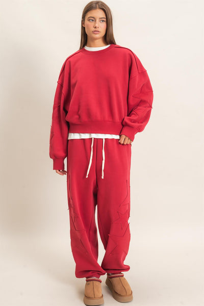 model wearing red start patch sweatshirt and matching joggers with a light background