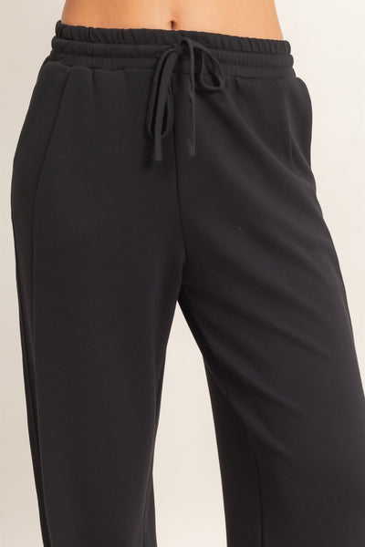 front view of model wearing black pants with a light background