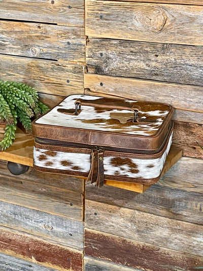 Brown and white cowhide patterned box on a wooden surface with a wooden wall background