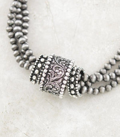 Silver beaded necklace with intricate rings on a light background