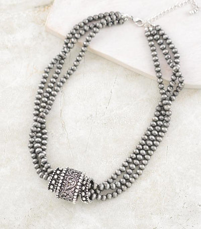 triple strand necklace with silver rings on a light background
