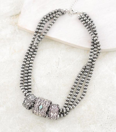 Silver beaded necklace with decorative rings on a light background