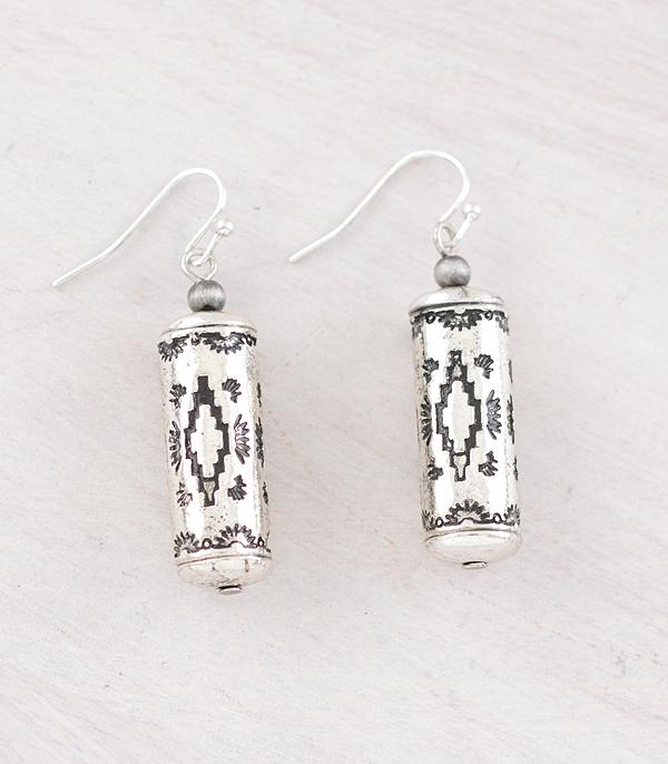 Silver cylindrical earrings with intricate patterns on a light gray background