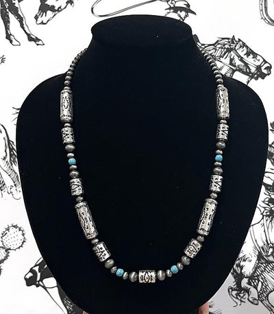 Necklace with beads on a black stand against a patterned background