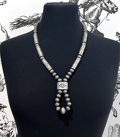 Silver beaded necklace on a black mannequin with a black and white patterned background