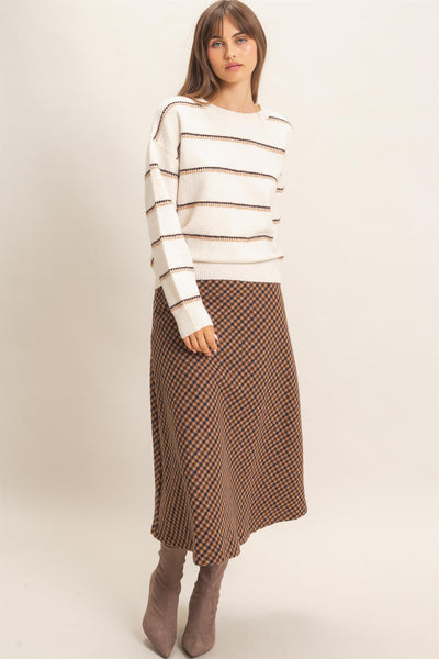 model wearing striped sweater and checkered skirt with a light background