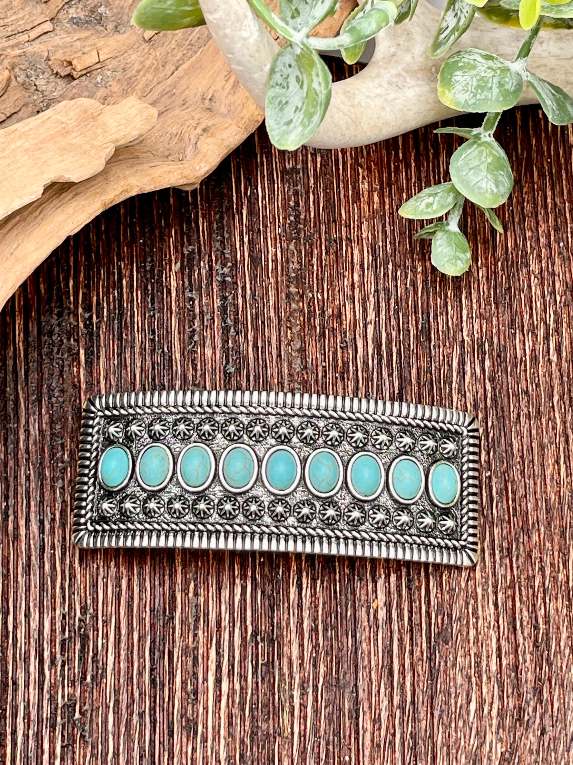 Silver barrette with turquoise stones on a wooden surface