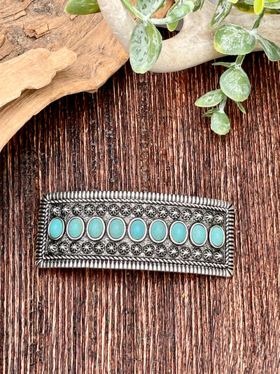Silver barrette with turquoise stones on a wooden surface