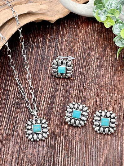 Silver jewelry set with turquoise stones on a wooden surface