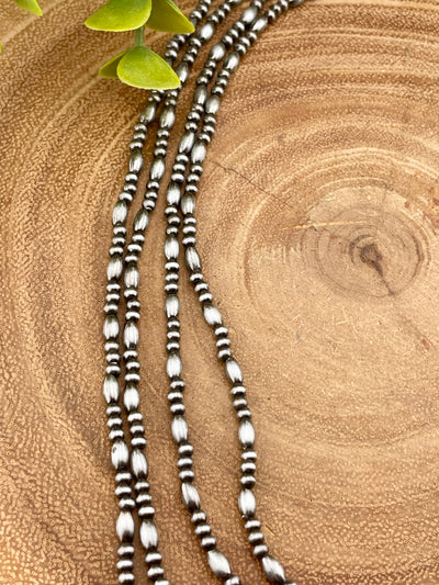 Close up of beaded necklaces on a wooden surface.