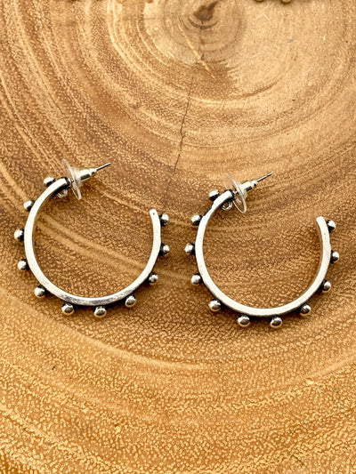 Silver hoop earrings with bead accents on a wooden surface