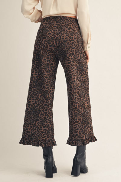 Leopard print pants worn by a person on a beige background