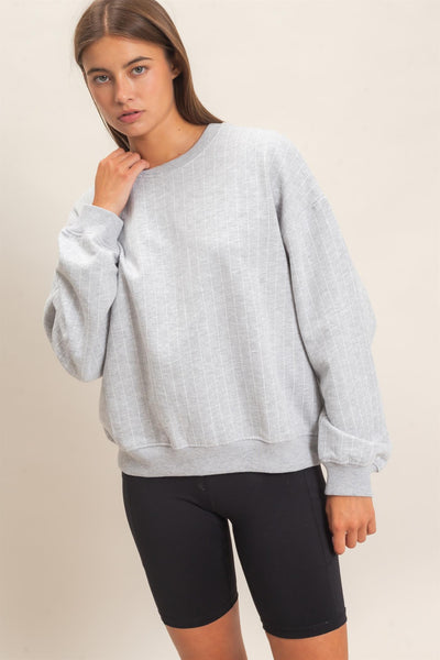 model wearing gray striped sweatshirt and black shorts with a light background