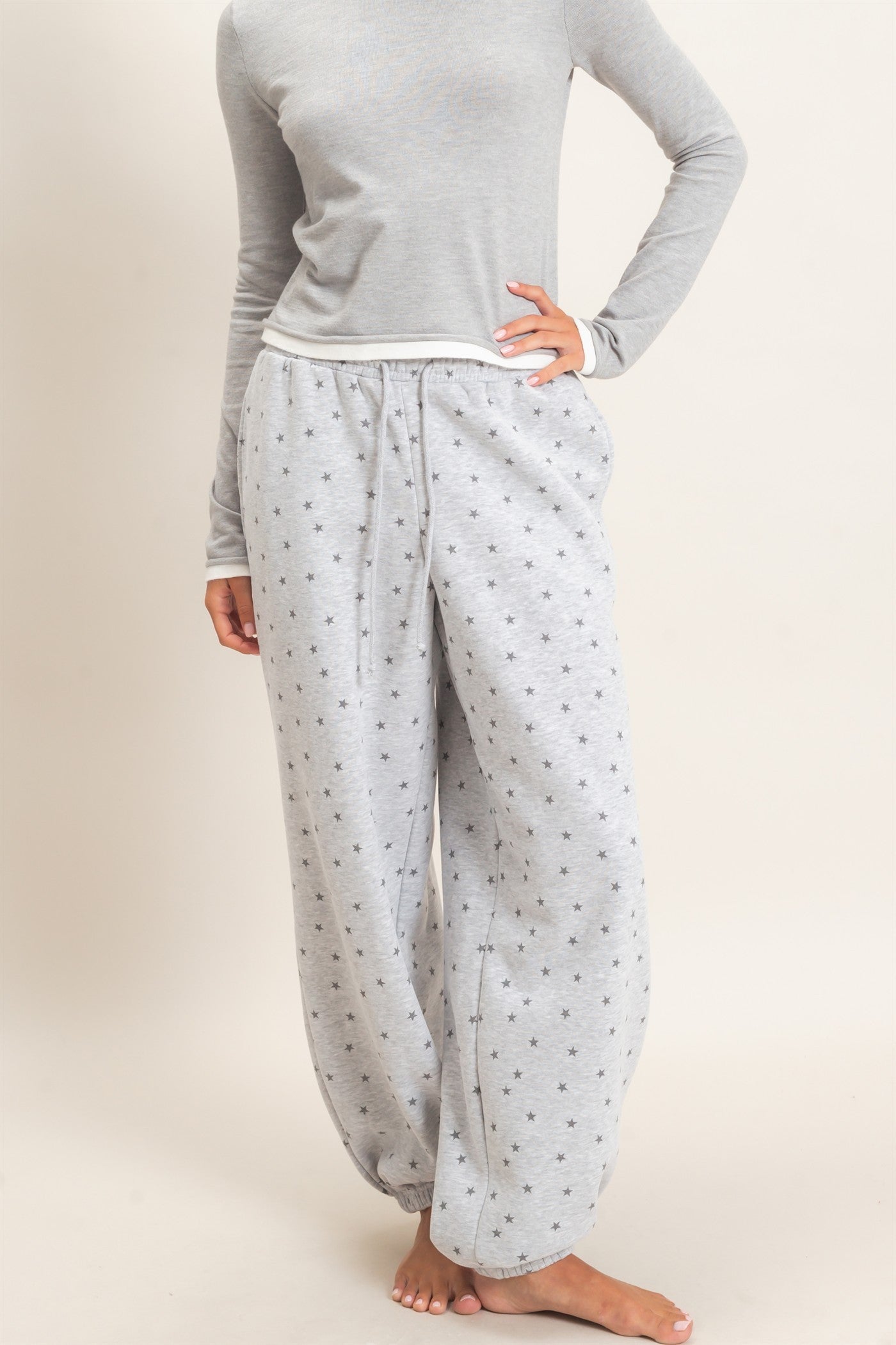 model wearing a gray top and gray joggers with stars