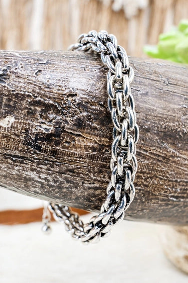 silver chain bracelet draped over a branch