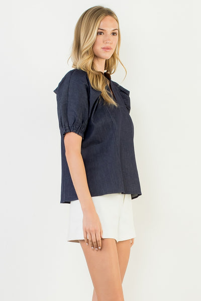 Woman wearing a navy blue top and white shorts on a light gray background