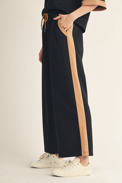 side view of person wearing black drawstring pants with side stripe.