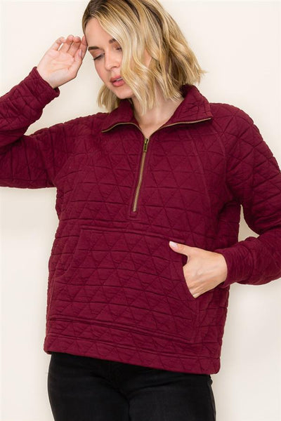 Woman wearing a burgundy quilted pullover against a plain background