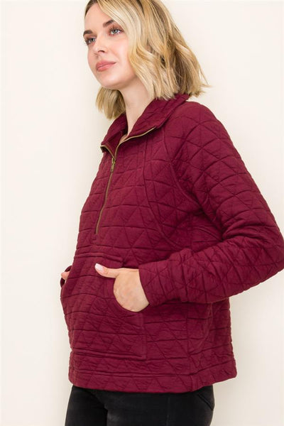 Woman wearing a burgundy quilted jacket against a white background