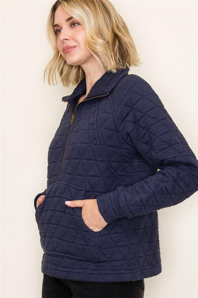 Woman wearing a navy quilted jacket against a plain background