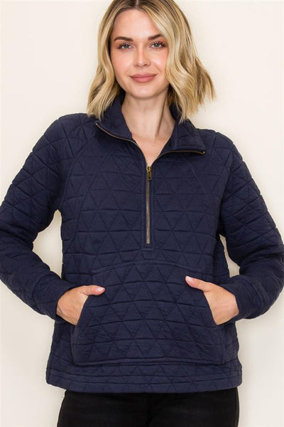 Woman wearing a navy quilted jacket against a plain background