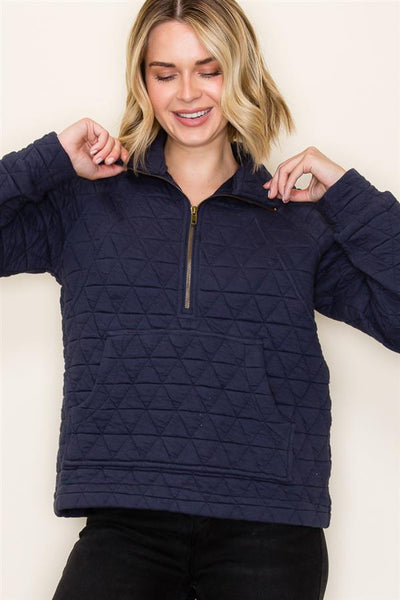 Woman wearing a navy quilted pullover against a plain background