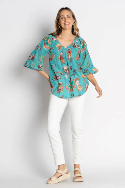 model wearing teal Mexican themed top with off white background