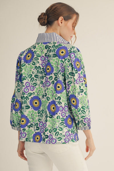 model wearing blue stripe & floral blouse with white pants on a light background