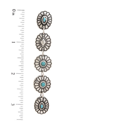 Silver earrings with turquoise stones on a white background with a ruler for scale.