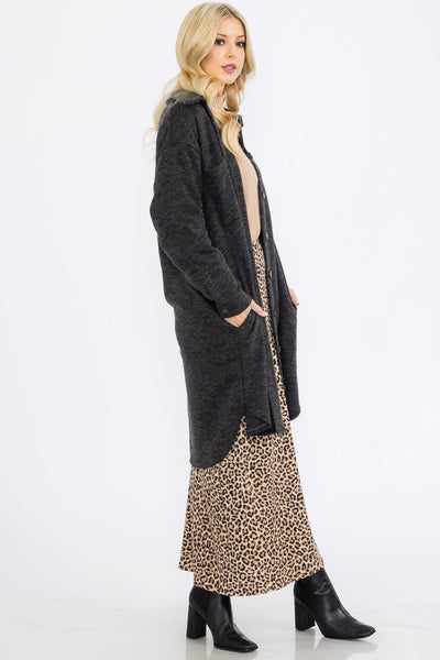 Woman wearing a long dark gray cardigan over a leopard print dress on a white background