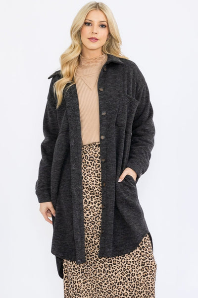 Woman wearing a long dark gray cardigan over a beige top and leopard print skirt on a white background