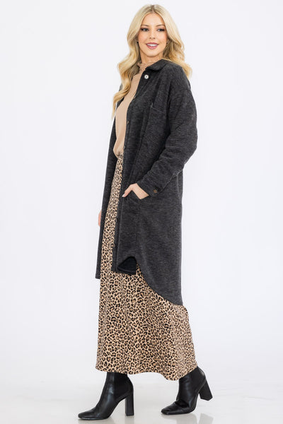 Woman wearing a long dark gray cardigan over a leopard print dress on a white background