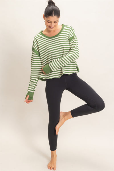 model wearing a green striped sweater and black pants with a light background