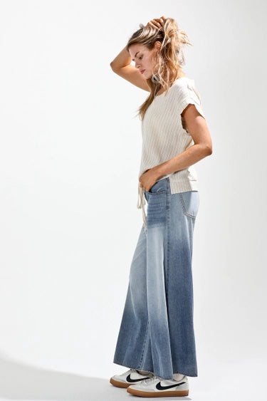 Woman wearing a white top and blue gradient pants on a white background