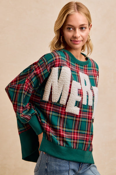 Woman wearing a plaid sweater with 'Merry' text on a beige background
