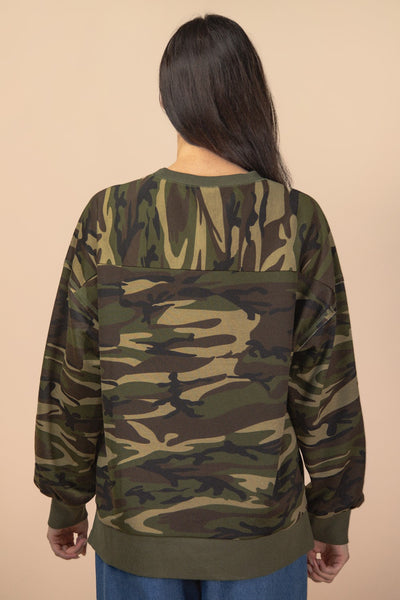 Person wearing a camouflage sweatshirt on a beige background