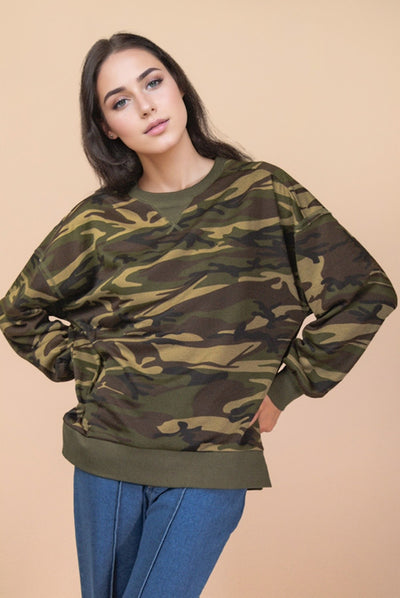 Woman wearing a camouflage sweater against a beige background