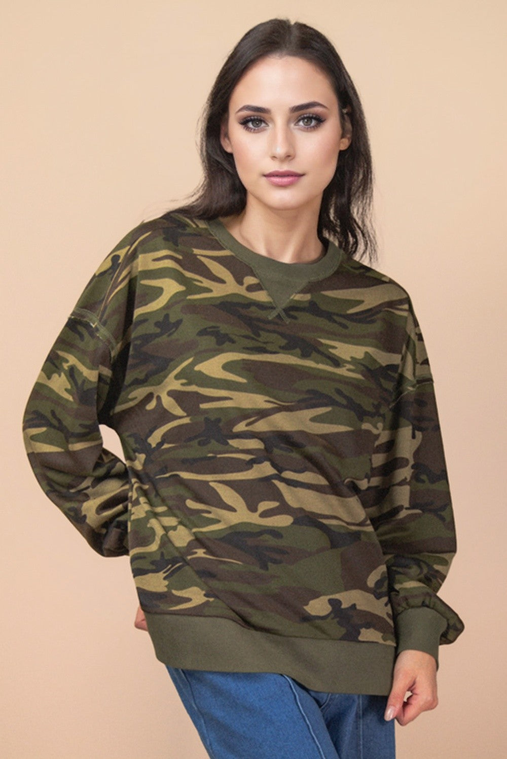 Woman wearing a camouflage sweater against a beige background