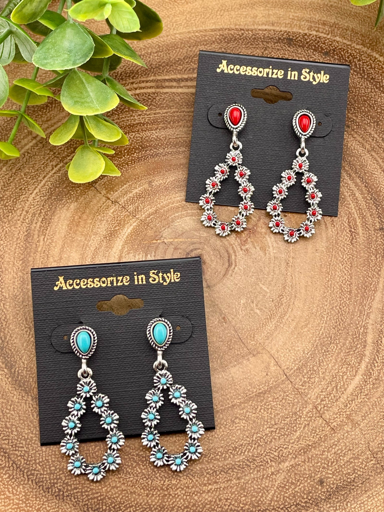 Pair of earrings with red and turquoise stones on 'Accessorize in Style' cards, placed on a wooden surface.