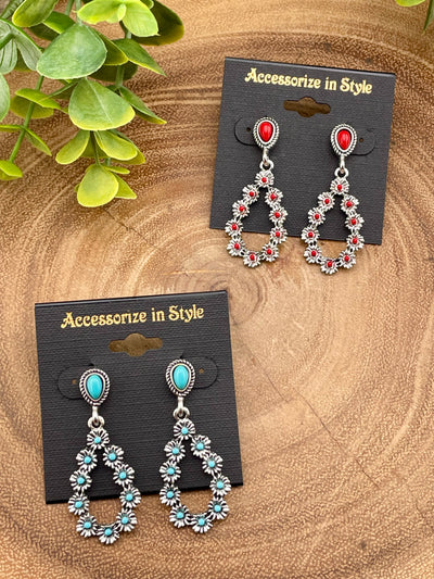 Pair of earrings with red and turquoise stones on 'Accessorize in Style' cards, placed on a wooden surface.
