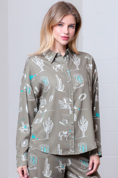 Woman wearing a patterned shirt with cacti and desert designs on a plain background