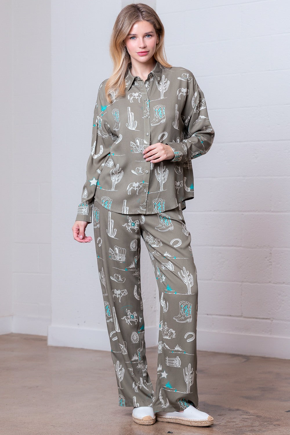 Woman wearing a matching shirt and pants set with nature-themed print against a white wall.