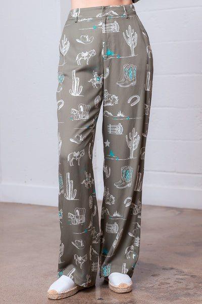 Green pants with western pattern worn by a person indoors.